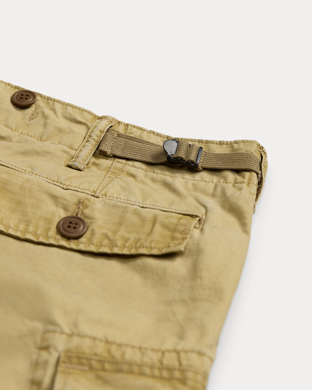 Close-up of beige pants with a button and strap on a white background
