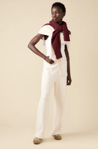 Woman wearing a white outfit with a burgundy scarf on a beige background