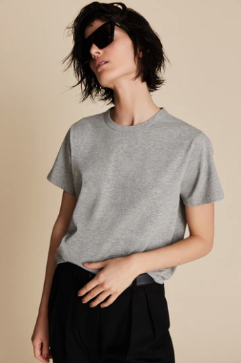 Person wearing a gray t-shirt and black sunglasses against a beige background