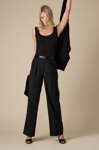 Woman wearing a black outfit with wide-leg pants and a black top against a beige background