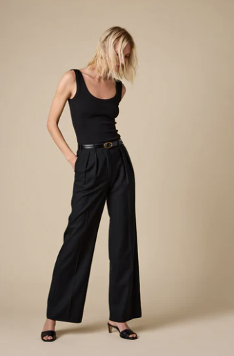 Woman wearing a black sleeveless top and wide-leg pants against a beige background