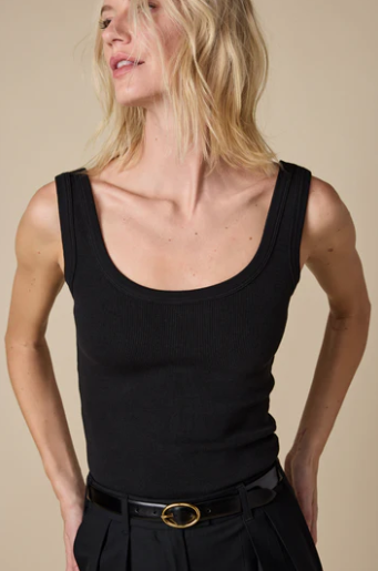 Woman wearing a black tank top with a beige background
