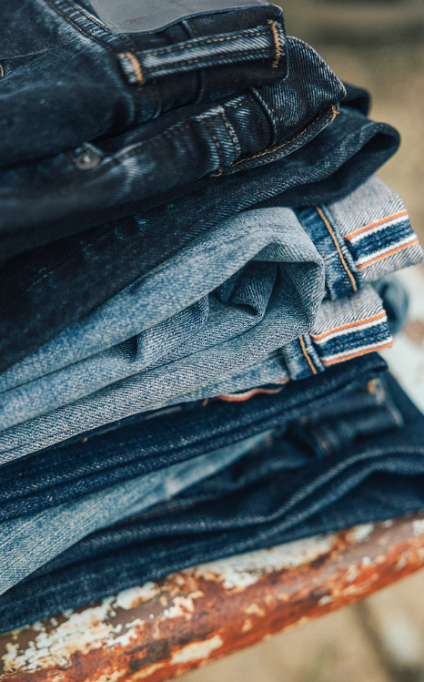 Stack of blue jeans on a rusty metal surface