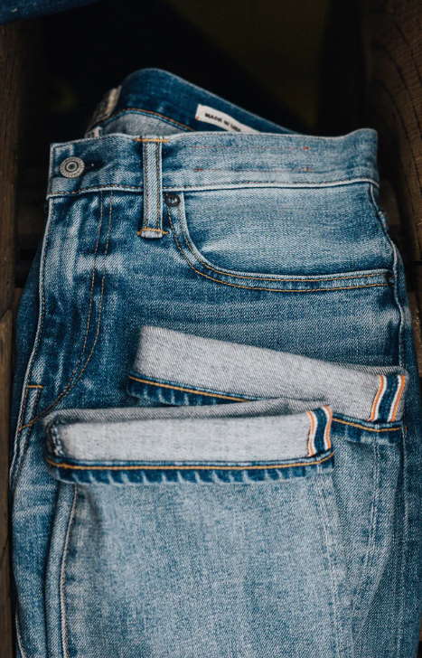 Stack of blue jeans with a dark background
