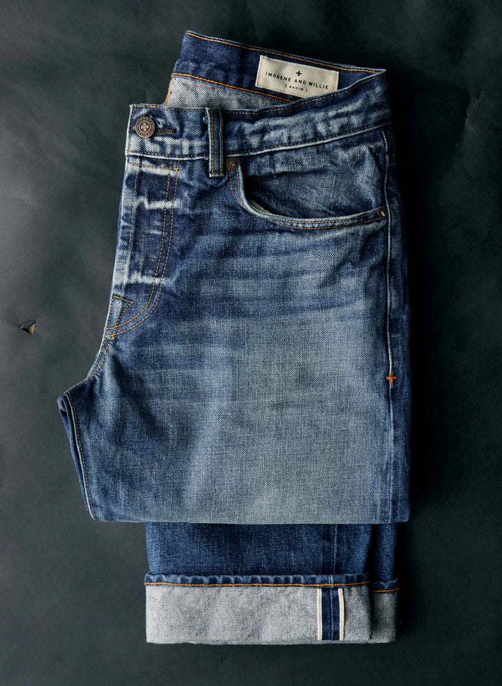 Stack of folded blue jeans on a dark surface