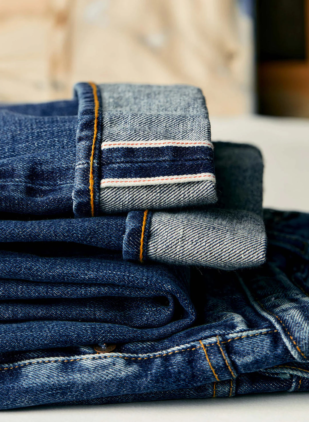 Stack of folded blue jeans on a wooden surface