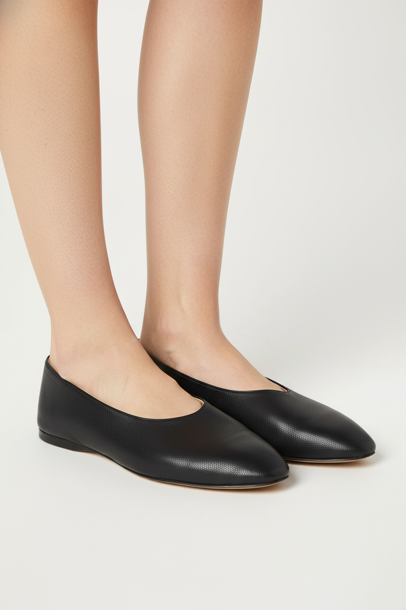 Black flat shoes worn with beige tights on a light gray background