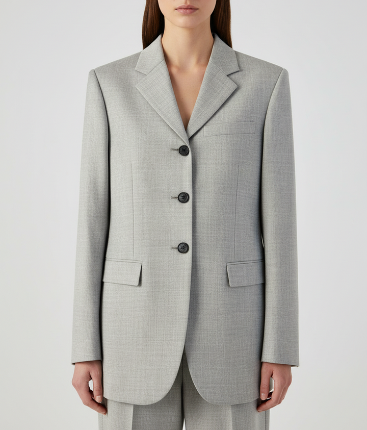 Woman wearing a light gray blazer with black buttons on a white background