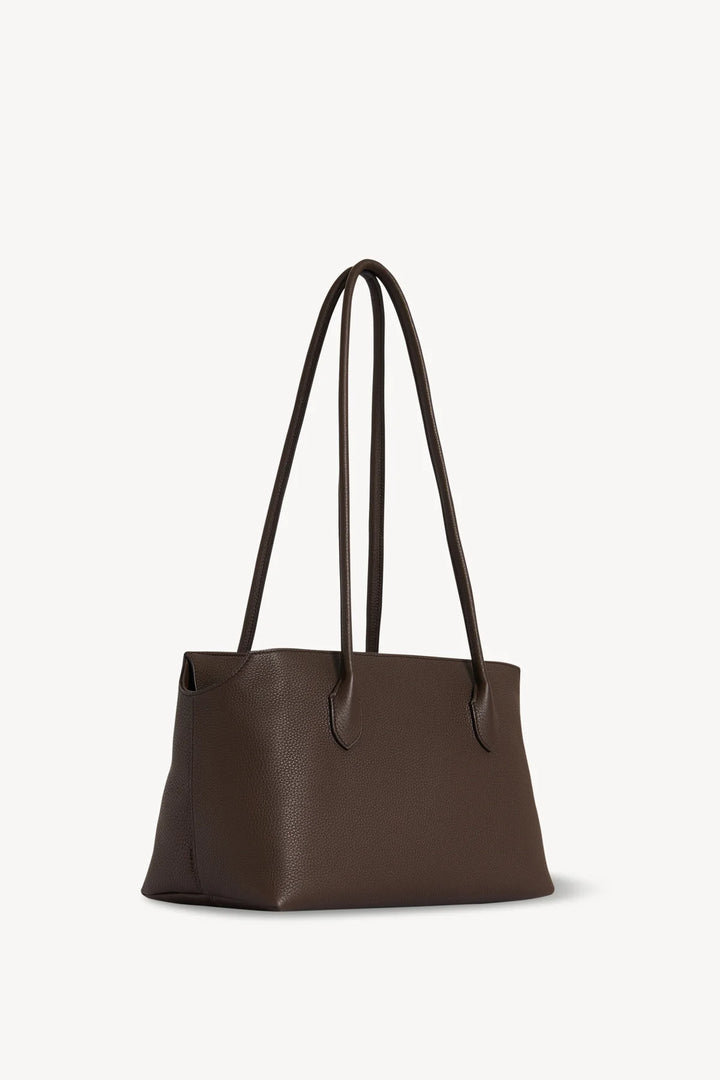 Brown leather tote bag with black handles on a white background