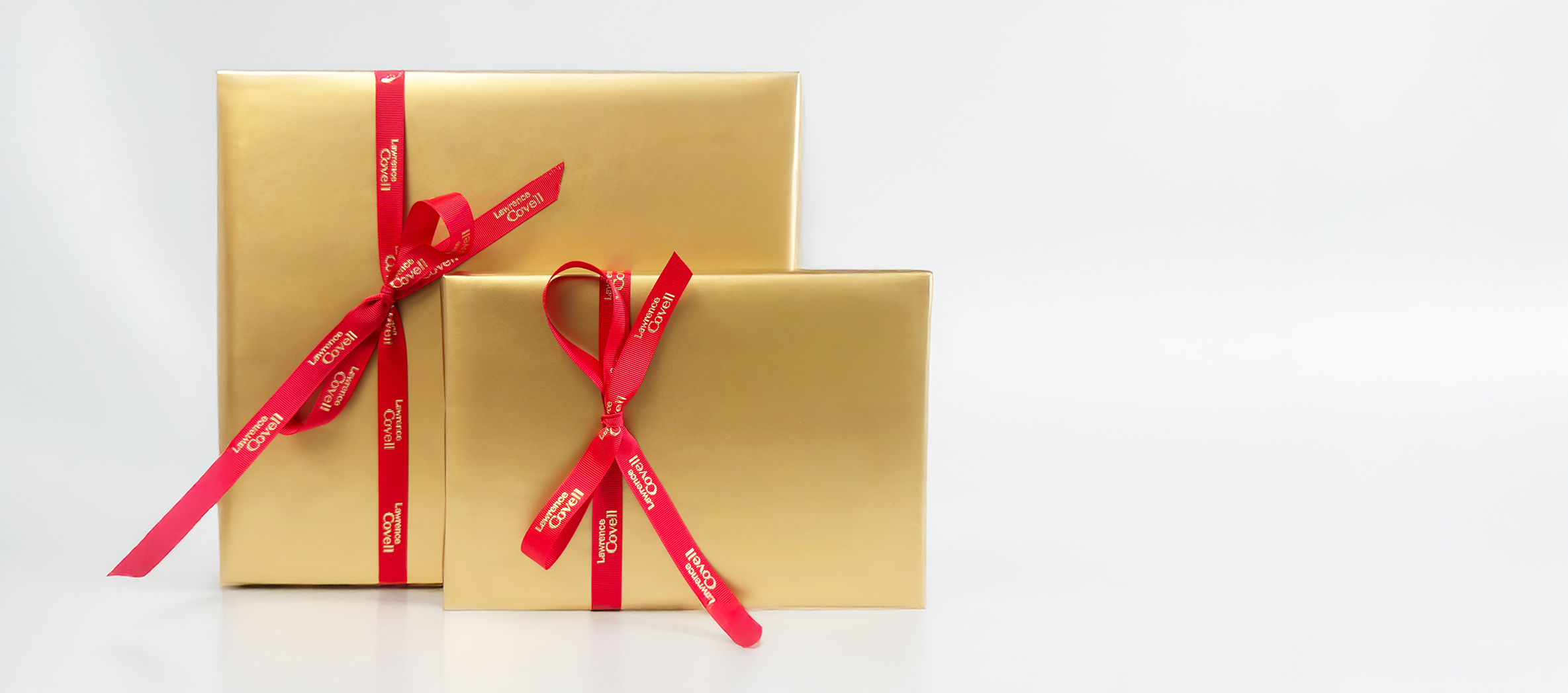 Two gold gift boxes with red ribbons on a white background