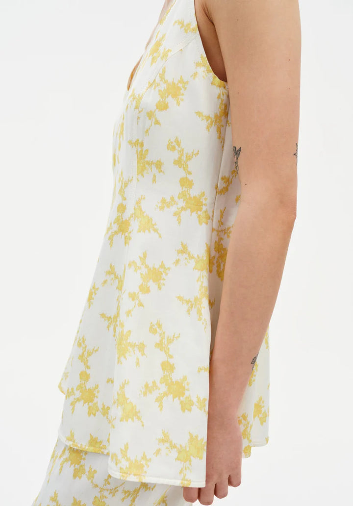 White dress with yellow floral pattern worn by a person on a white background