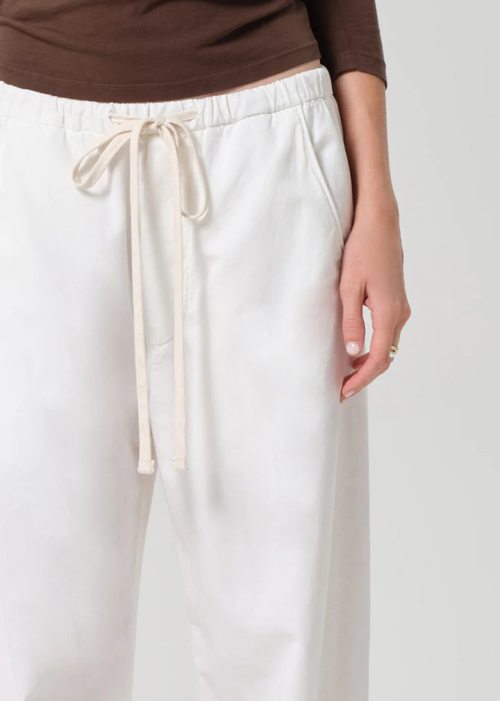 White pants with a drawstring waist worn by a person on a white background