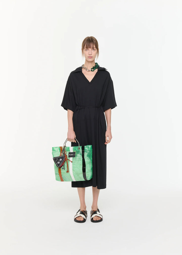 Woman holding a green and black patterned bag against a white background
