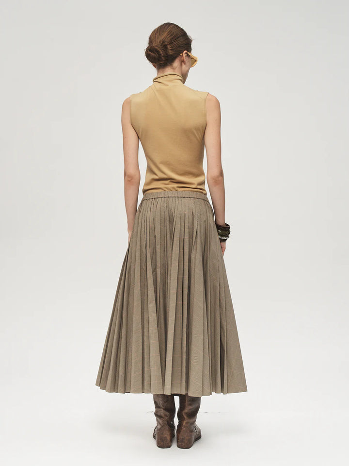 Woman wearing a beige sleeveless top and pleated skirt on a white background