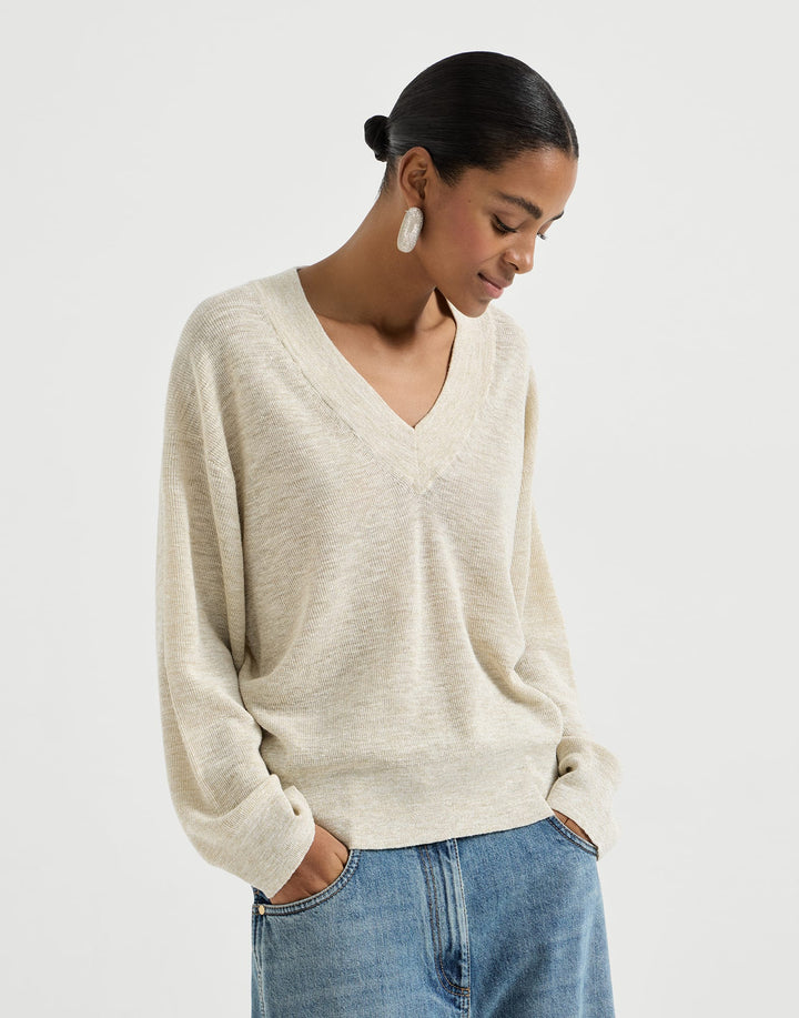 Woman wearing a beige sweater and blue jeans on a white background