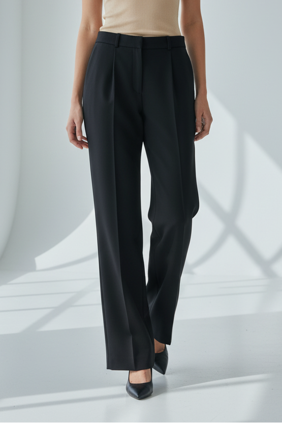 Woman wearing a beige tank top and black pants in a bright room with sunlight filtering through.