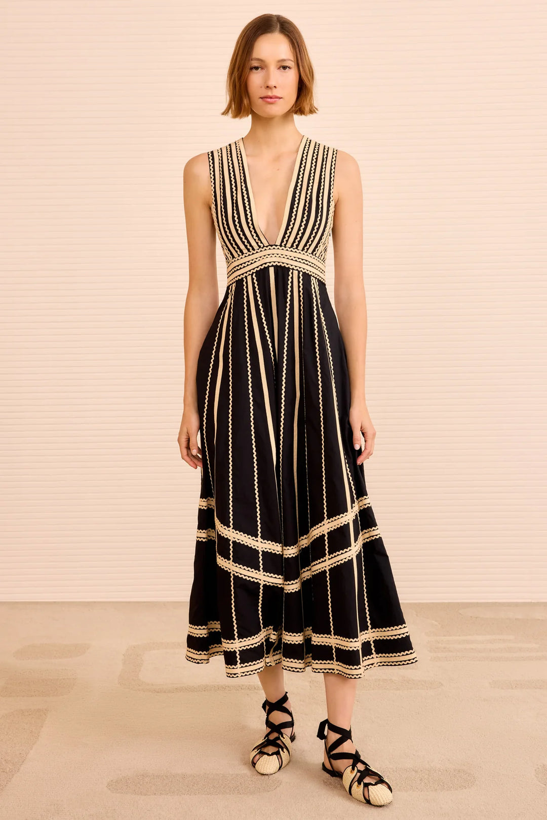 Woman wearing a black and gold dress with a plain background