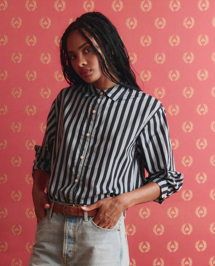 Woman wearing a black and white striped shirt against a pink background with a subtle pattern.