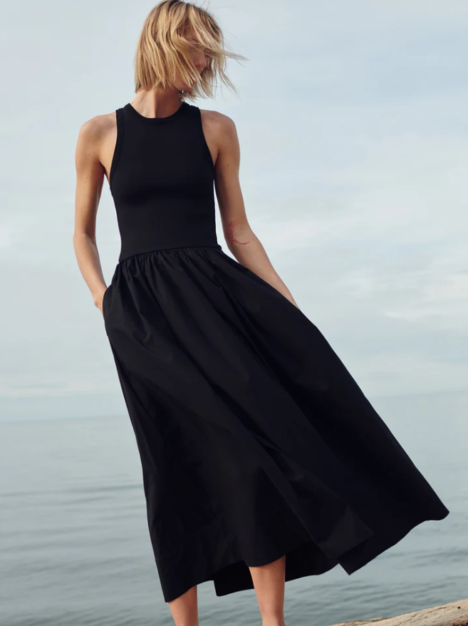 Woman wearing a black dress standing by a body of water