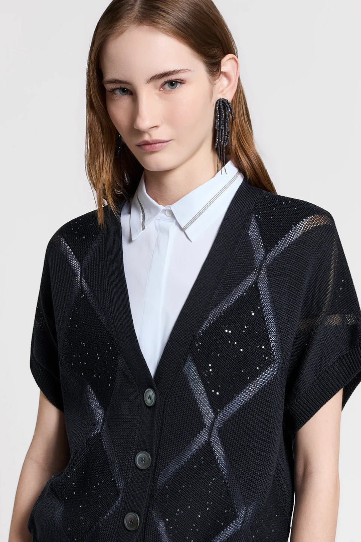 Woman wearing a black patterned cardigan over a white shirt on a light gray background