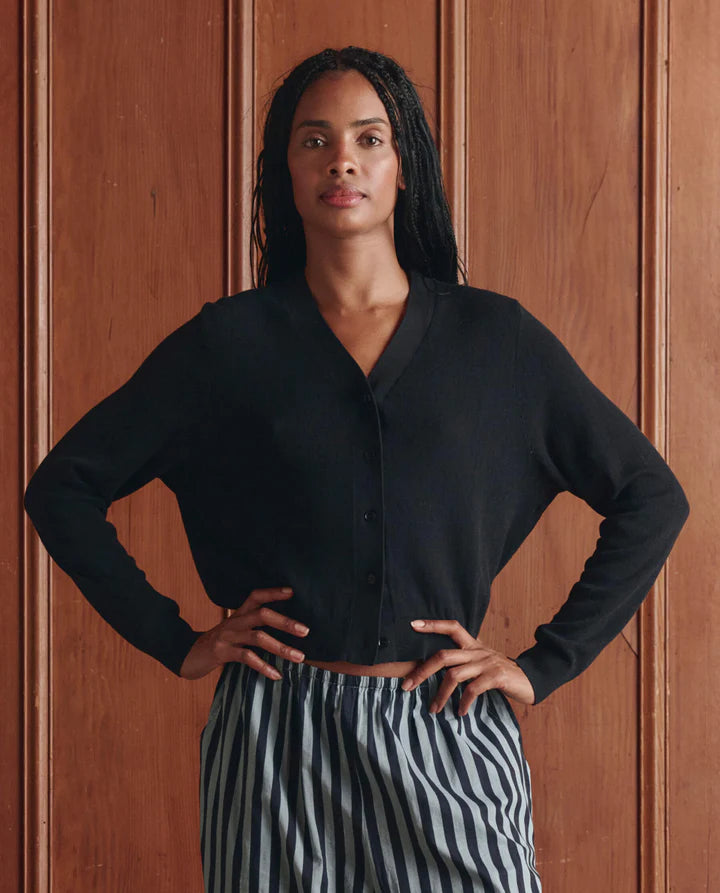 Woman wearing a black shirt and striped pants against a wooden panel background