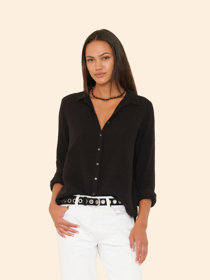 Woman wearing a black shirt and white pants on a beige background