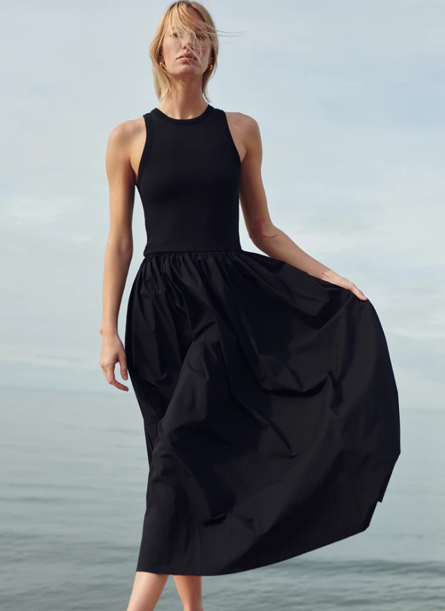 Woman wearing a black sleeveless dress against a gray background
