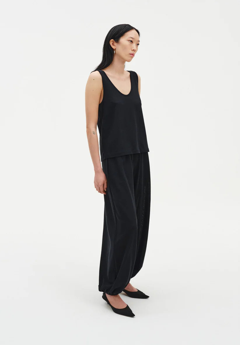 Woman wearing a black sleeveless top and wide-leg pants on a white background
