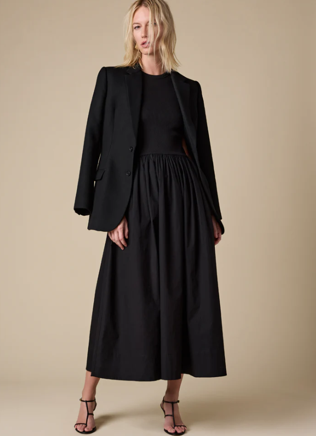 Woman wearing a black suit with a long skirt on a beige background