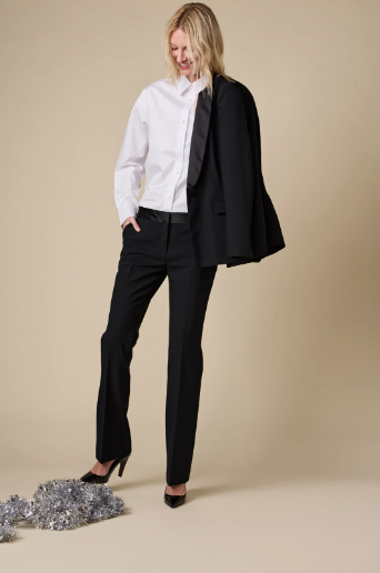 Woman wearing a black suit with a white shirt on a beige background