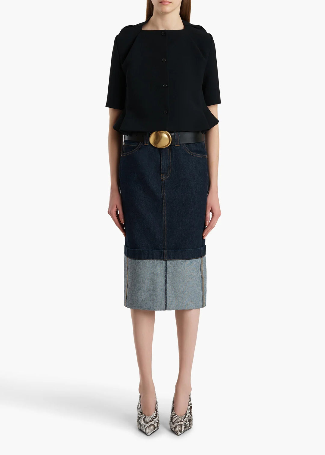 Woman wearing a black top and denim skirt with a white background