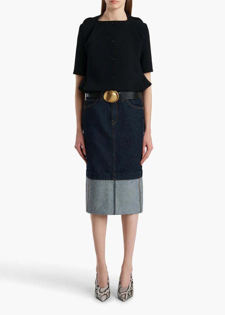 Woman wearing a black top and denim skirt with a white background