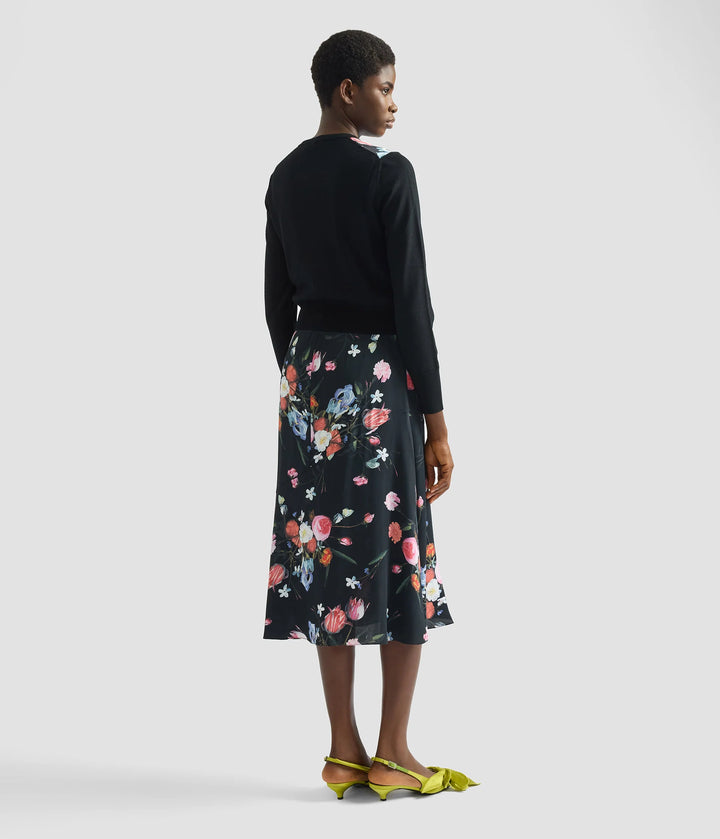 Woman wearing a black top and floral skirt on a white background