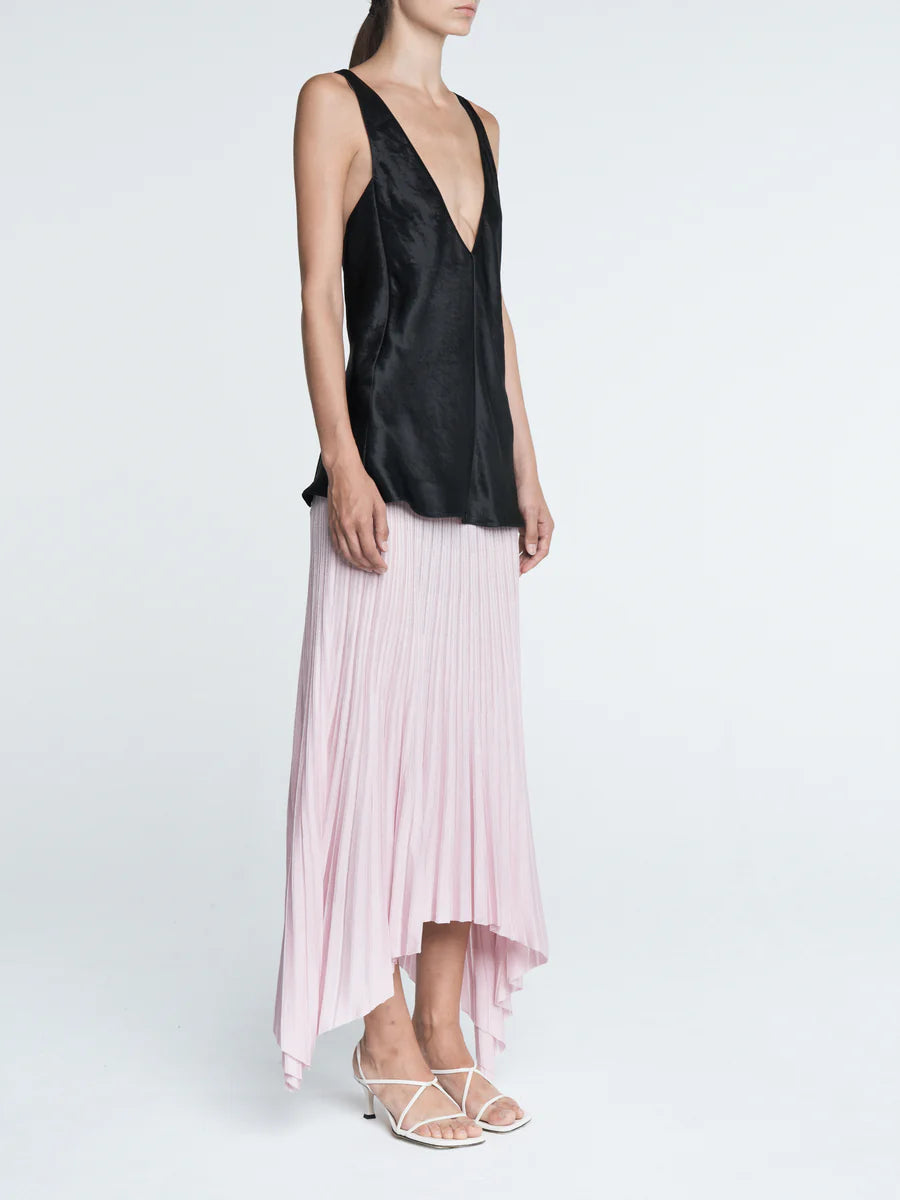 Woman wearing a black top and pink pleated skirt on a white background