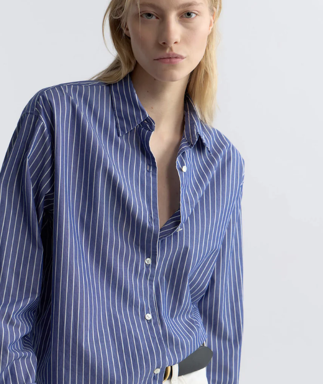Woman wearing a blue and white striped shirt against a plain background