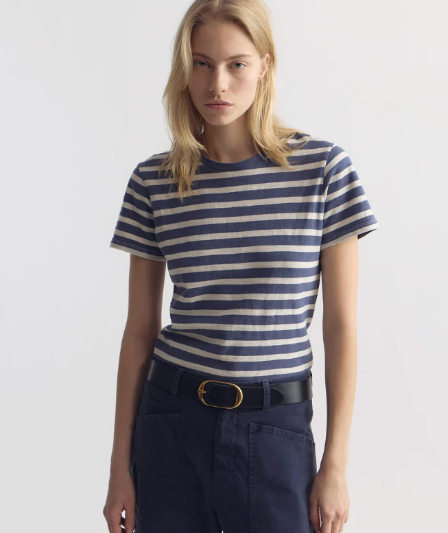 Woman wearing a blue and white striped shirt with navy pants on a light gray background