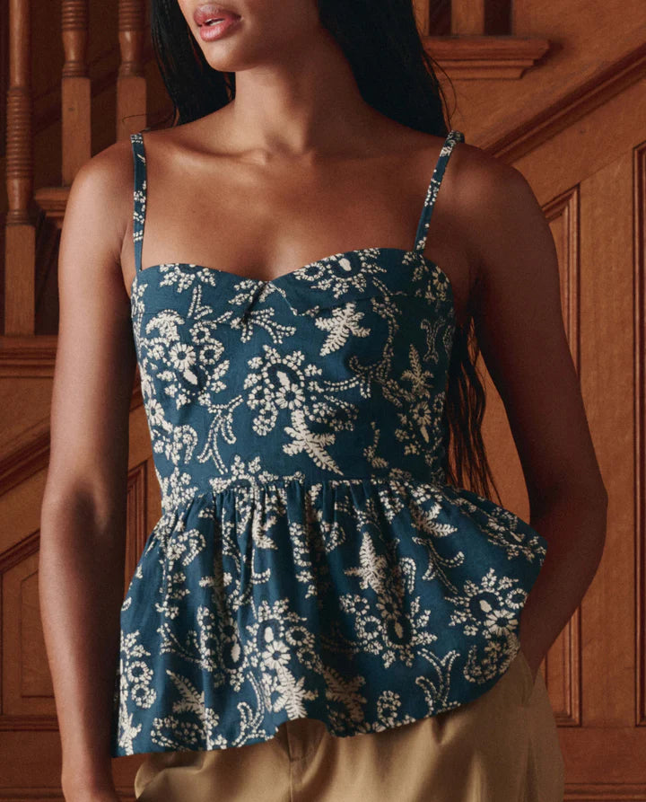 Woman wearing a blue floral peplum top against a wooden background