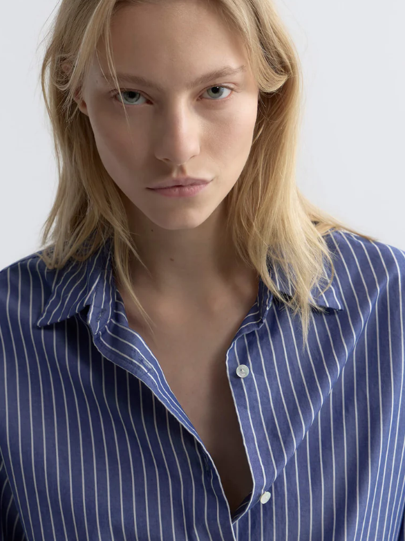 Woman wearing a blue pinstripe shirt against a white background