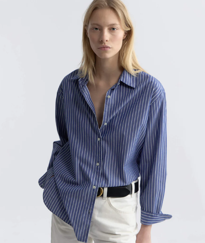 Woman wearing a blue striped shirt with a plain background