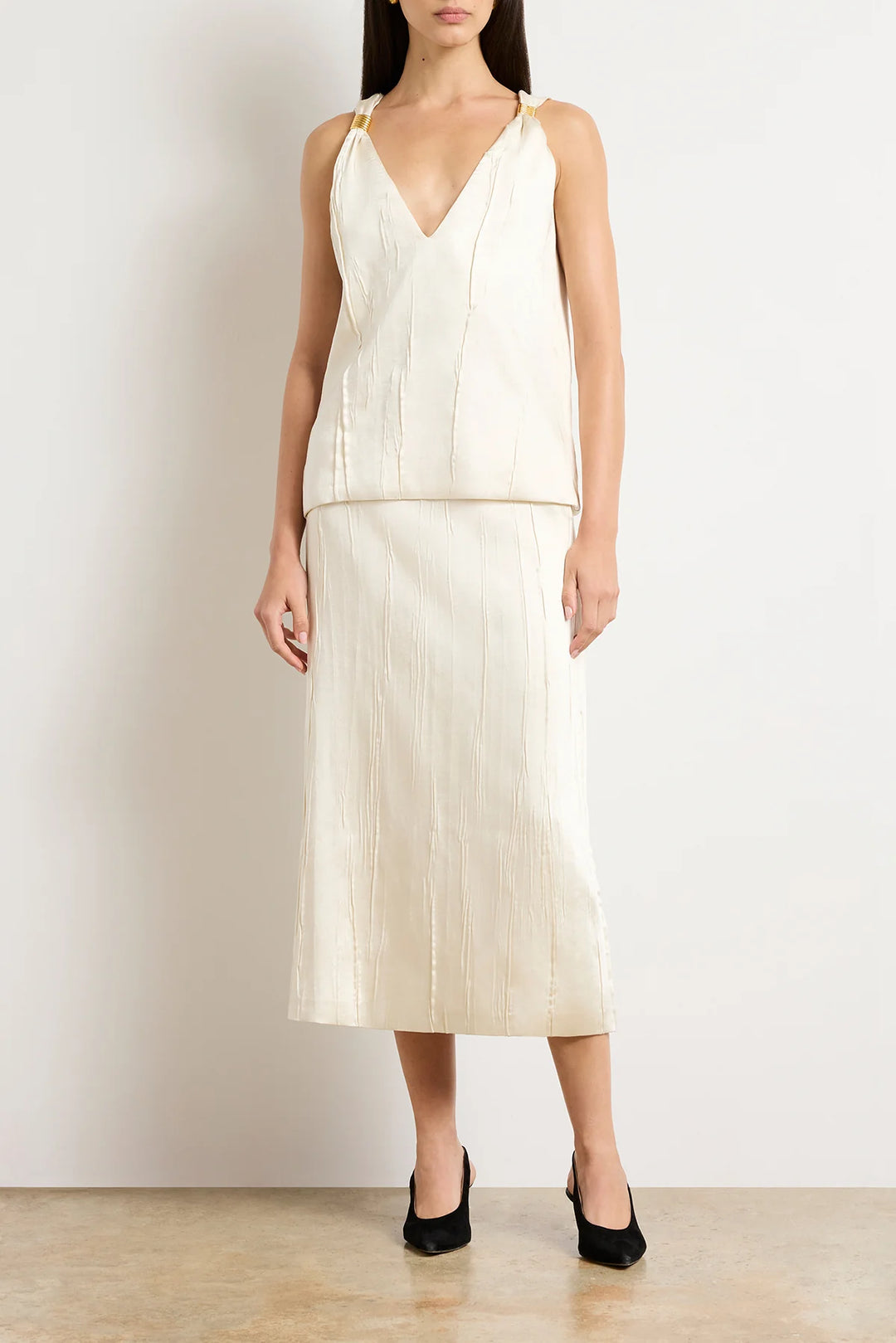 Woman wearing a cream-colored dress with a plain background