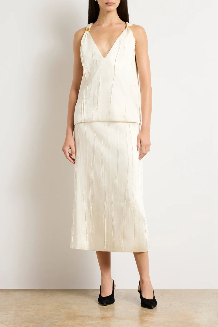 Woman wearing a cream-colored dress with a plain background