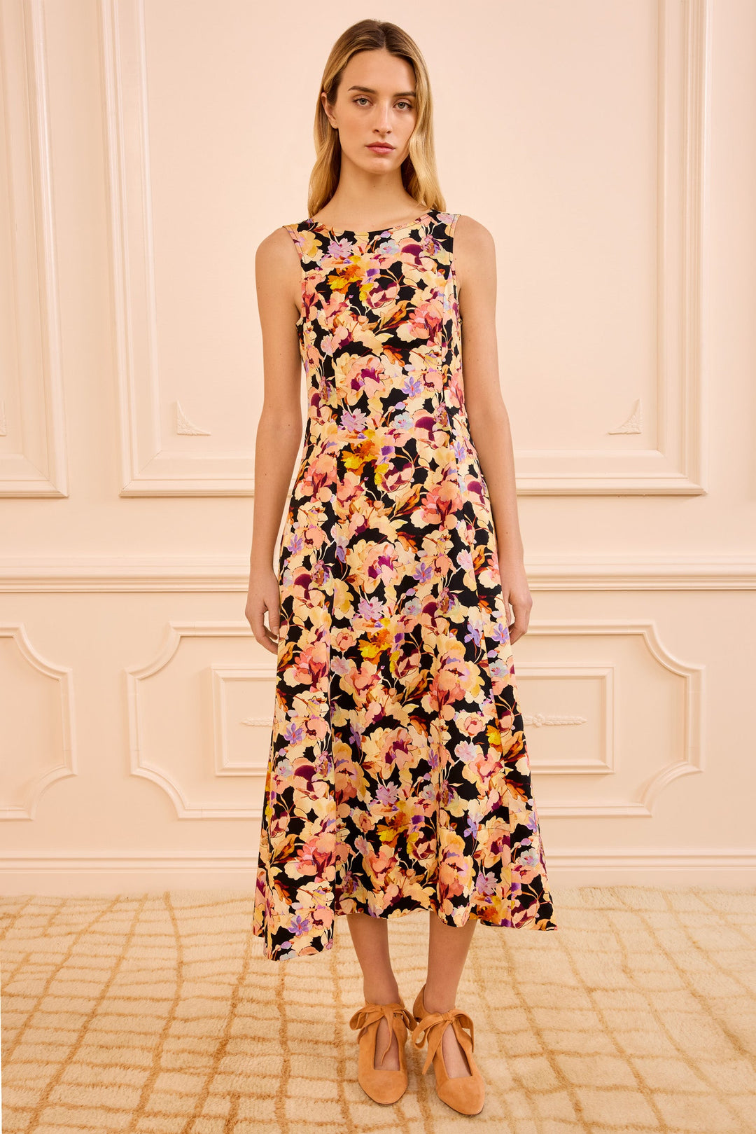 Woman wearing a floral dress against a light pink wall.