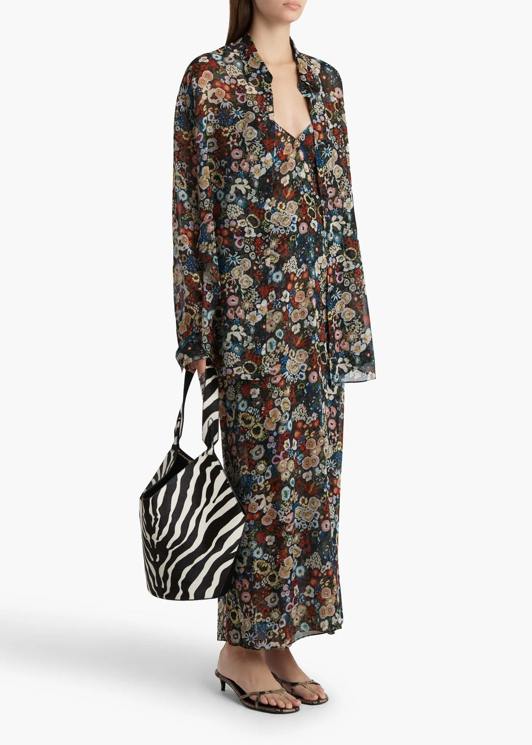 Woman wearing a floral dress holding a zebra-striped bag on a white background