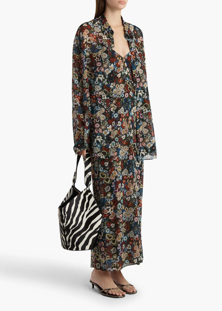 Woman wearing a floral dress holding a zebra-striped bag on a white background