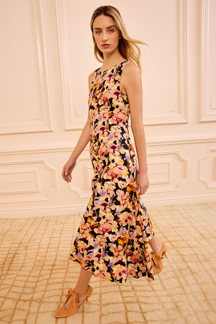 Woman wearing a floral dress in a room with decorative walls.