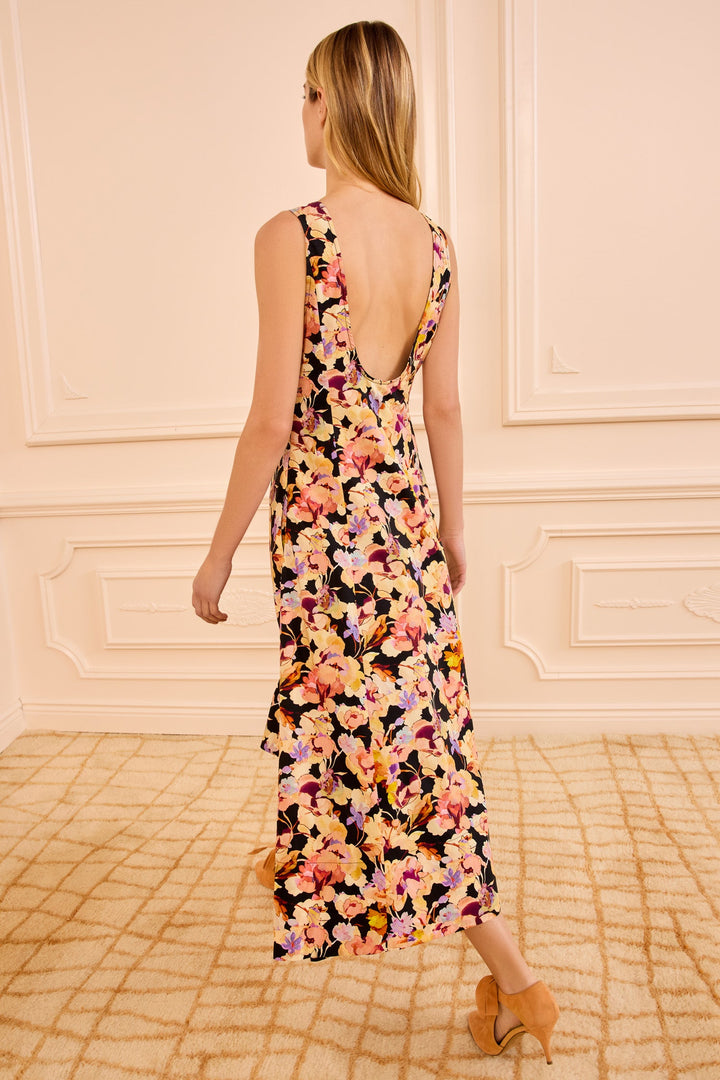 Woman wearing a floral dress in a room with decorative walls and a patterned rug.