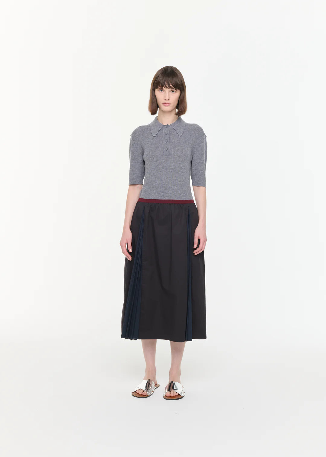 Woman wearing a gray sweater and black skirt on a white background