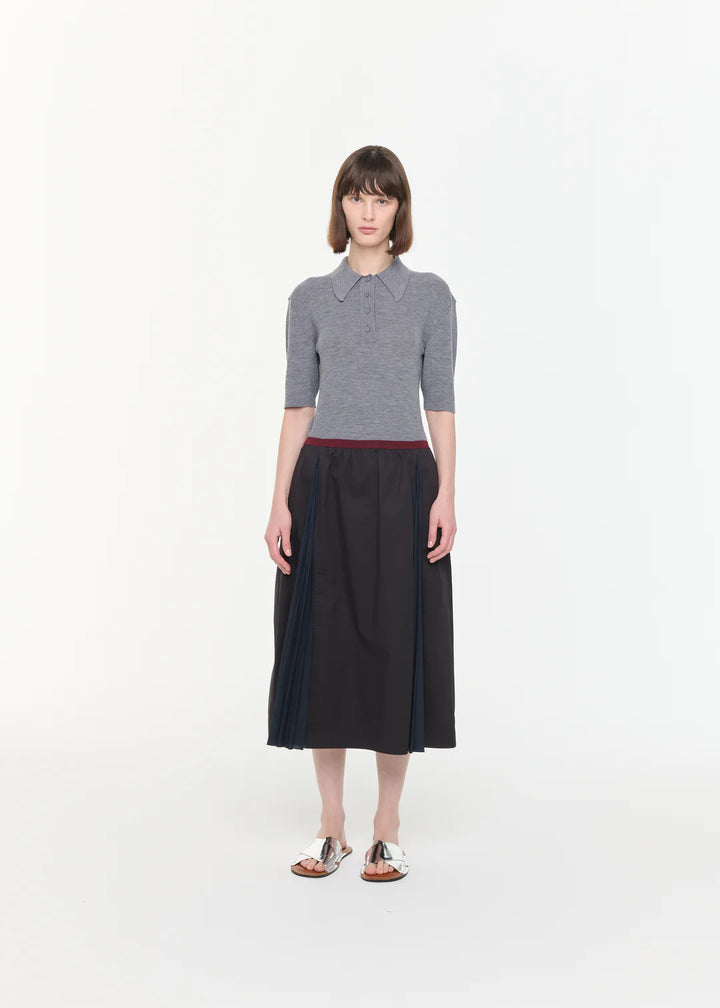 Woman wearing a gray sweater and black skirt on a white background