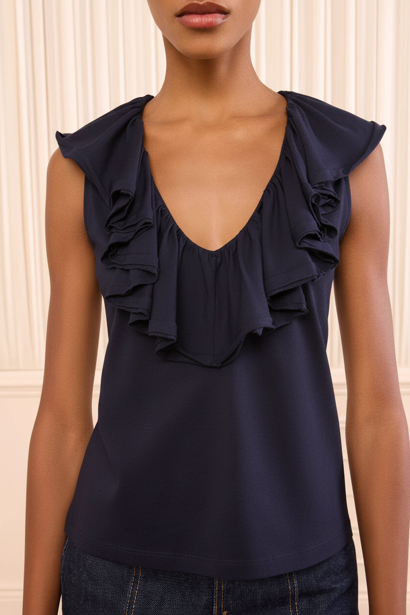 Woman wearing a light-colored blouse with ruffled details against a neutral background