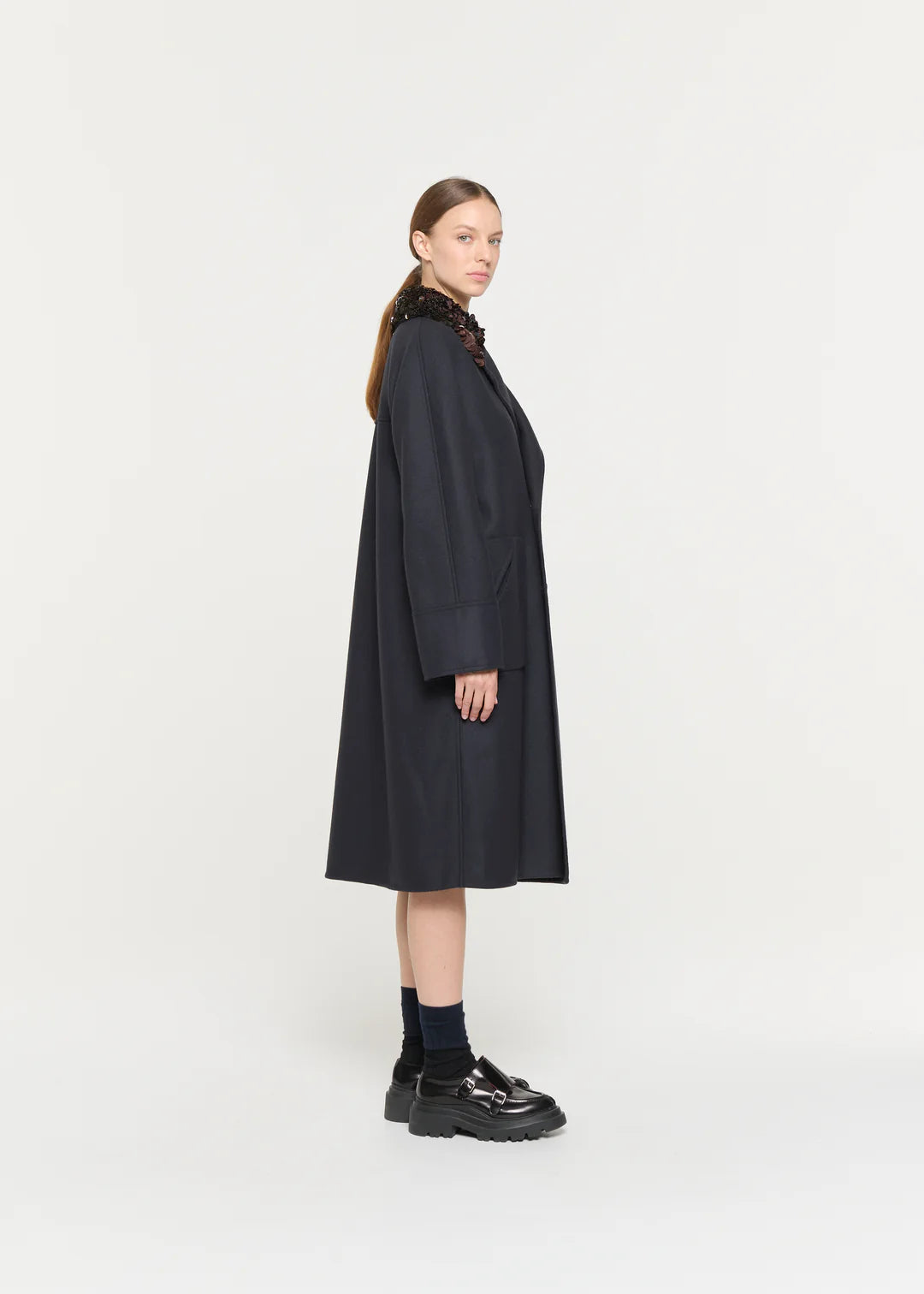 Woman wearing a long dark coat on a white background